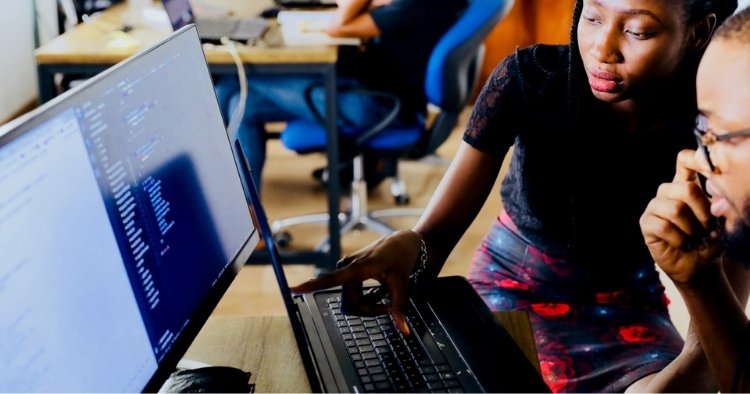 One person teaching another while working on a computer represent STACK's apprenticeship program