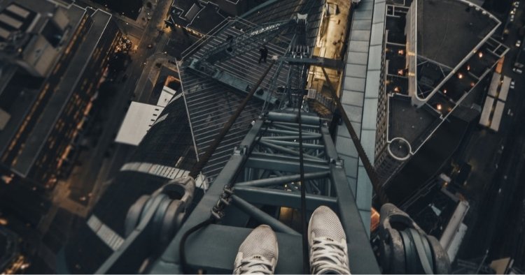 Person standing on top of a crane representing risk
