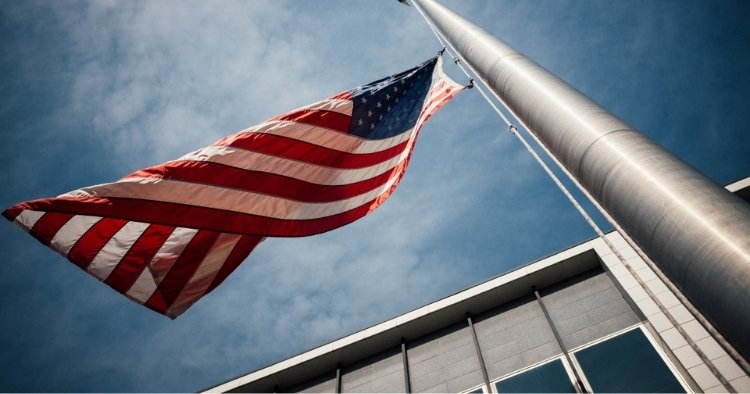 United States of America flag on flag pole waving in the wind representing changes to CMMC made by the government