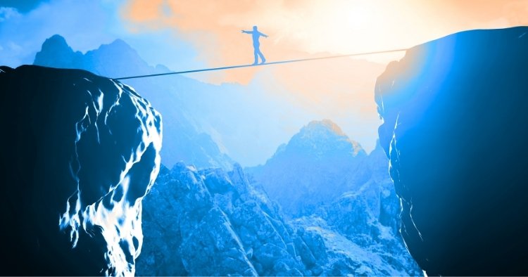 Person walking between two mountains on a high wire