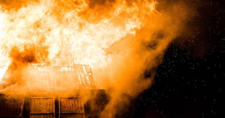 Burning building with sparks flying showing disaster that can be prevented by Cyber Insurance