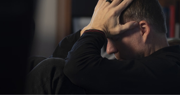 A man with his head in his hands after becoming a victim to a data breach