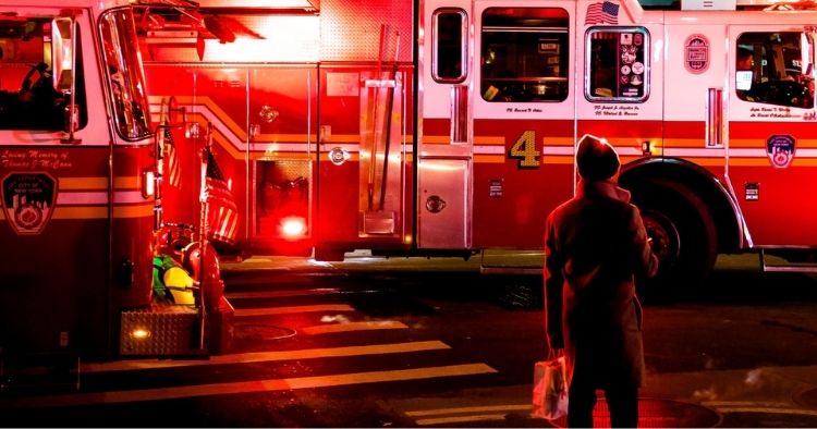 Man standing in front of two fire trucks with their lights on representing incident response