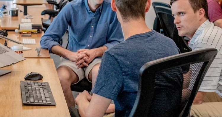 Three coworkers in deep discussion sitting at a desk