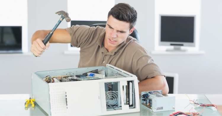 Boy hitting computer with hammer in office